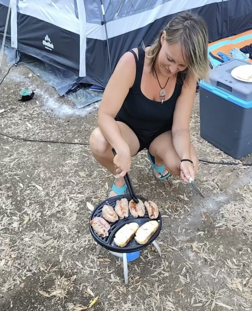 Person bereitet beim Camping draußen eine Mahlzeit in einer Pfanne zu Die beste Camping-Ausrüstung 