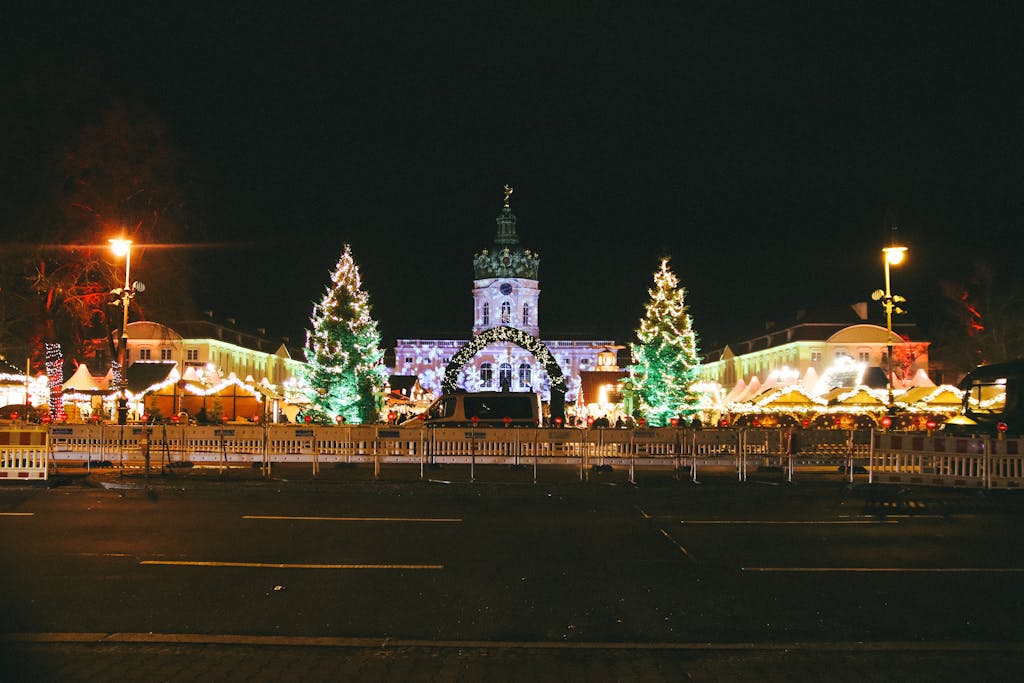 A vibrant Christmas market scene with lights and decorations in front of Charlottenburg Palace, Berlin.