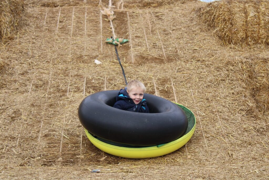 Kind auf einer Reifenrutsche aus Strohballen auf dem Krewelshof in Mechernich-Kommern