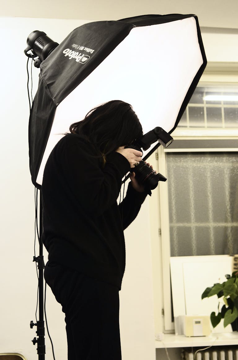 Photographer in action with studio lighting equipment capturing the perfect shot indoors.