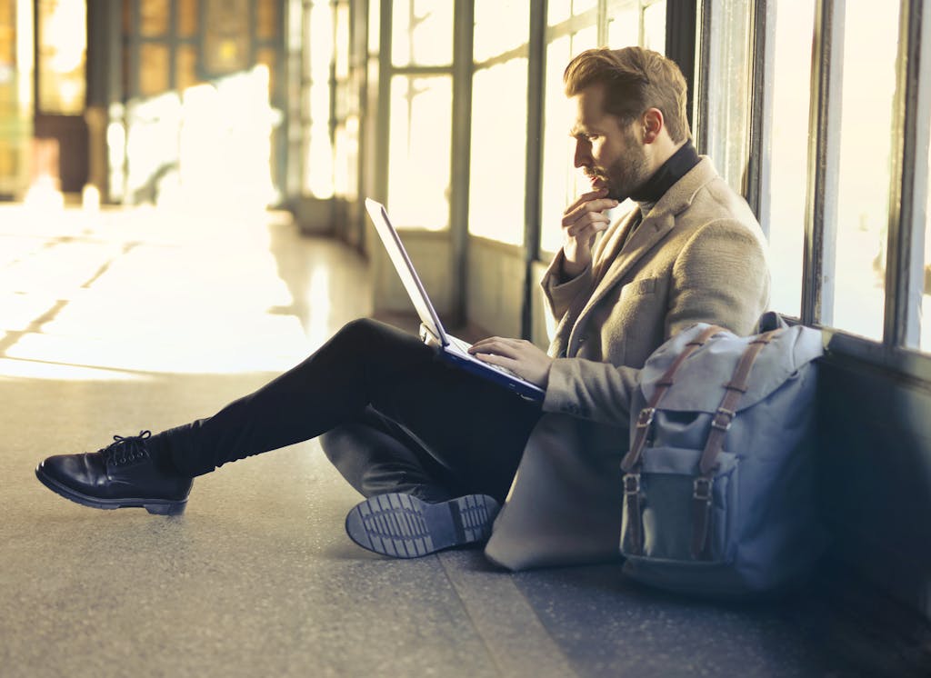 Flug verspätet? So forderst du jetzt deine Entschädigung richtig ein young man sitting indoors at an airport using laptop. ideal for remote work themes. 842921 Junger Mann arbeitet am Laptop während er am flughafen auf seinen verspäteten flug wartet Flug verspätet