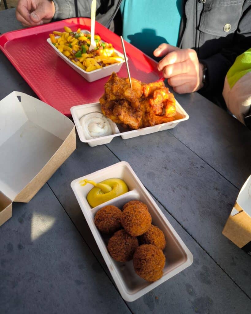 Camping in Burgh-Haamstede: Unsere Tipps für den Familienurlaub in den Niederlanden campingplatz bugh haamstede am meer 3 Verschiedene frittierte Snacks und Salate auf einem dunklen Tisch, Street Food Genuss.