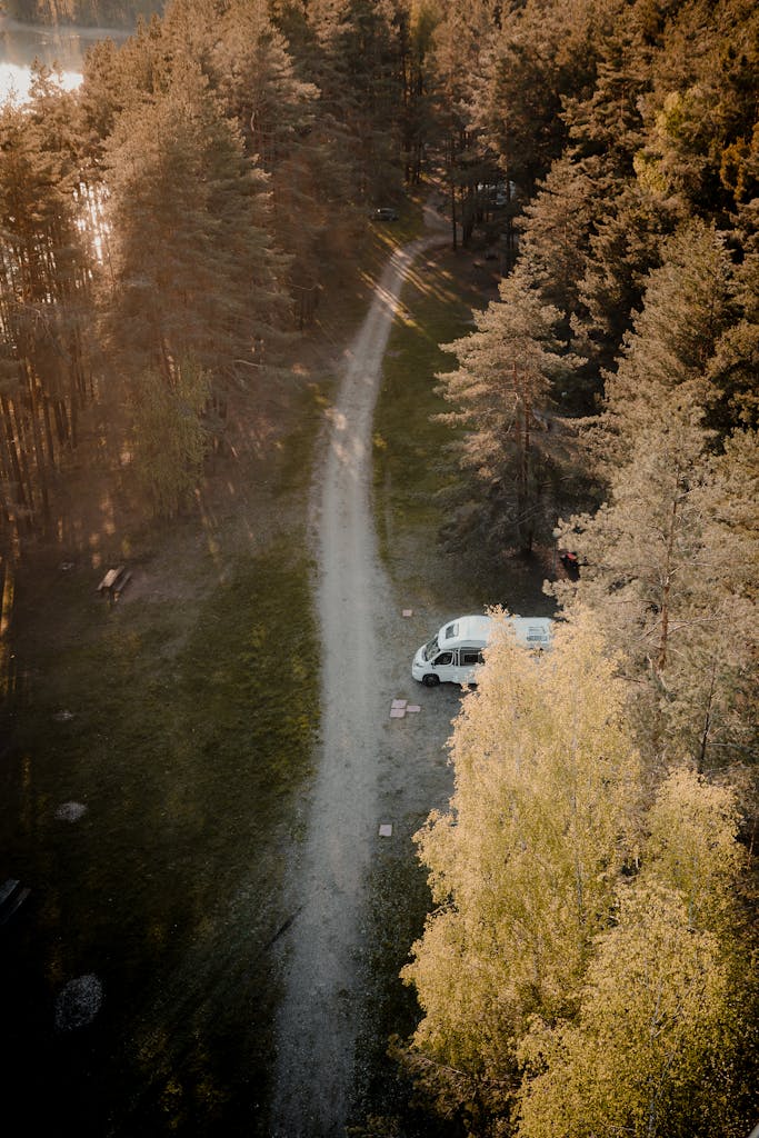 Die richtige Unterkunft finden: Hotel, Ferienwohnung oder Camping drone captures a serene forest road in lithuania with a parked white van surrounded by lush trees. 7918536 wohnmobil mieten