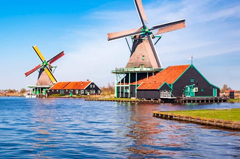 Reiseziele entdecken – unsere Reisen & Tipps & Inspiration picturesque view of traditional dutch windmills by a lake under a clear blue sky. 13059436 Urlaub in den Niederlanden – Tipps, Regionen & Reiseplanung