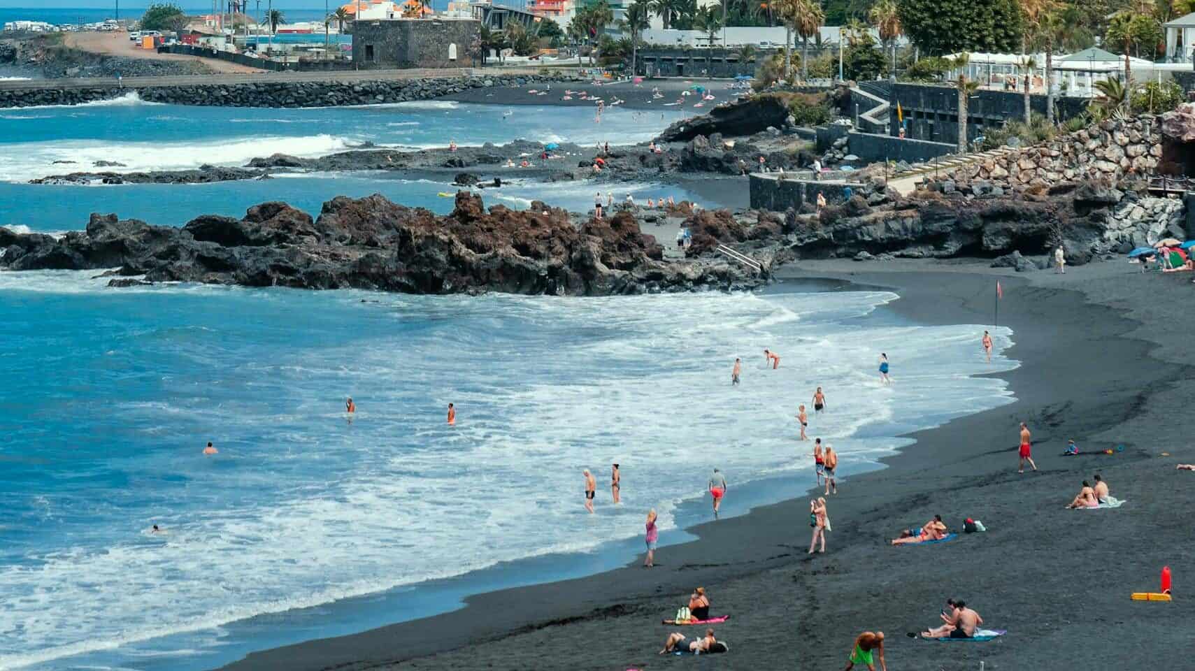 Die schönsten Strände auf Teneriffa – schwarze Sandstrände & versteckte Buchten relaxing day at puerto de la cruzs unique black sand beach with cityscape view. 13642622 scaled edited Playa Jardín (Norden) Puerto de la Cruz's