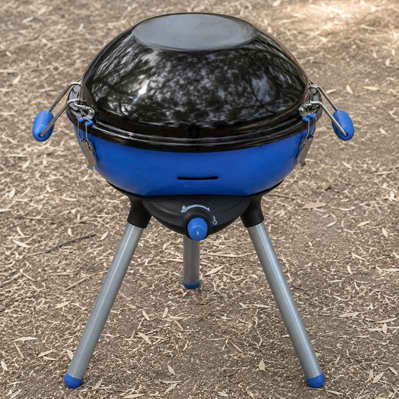 Blauer Campingaz Party Grill auf trockenem Campingboden für Zelturlaub und Auto-Camping