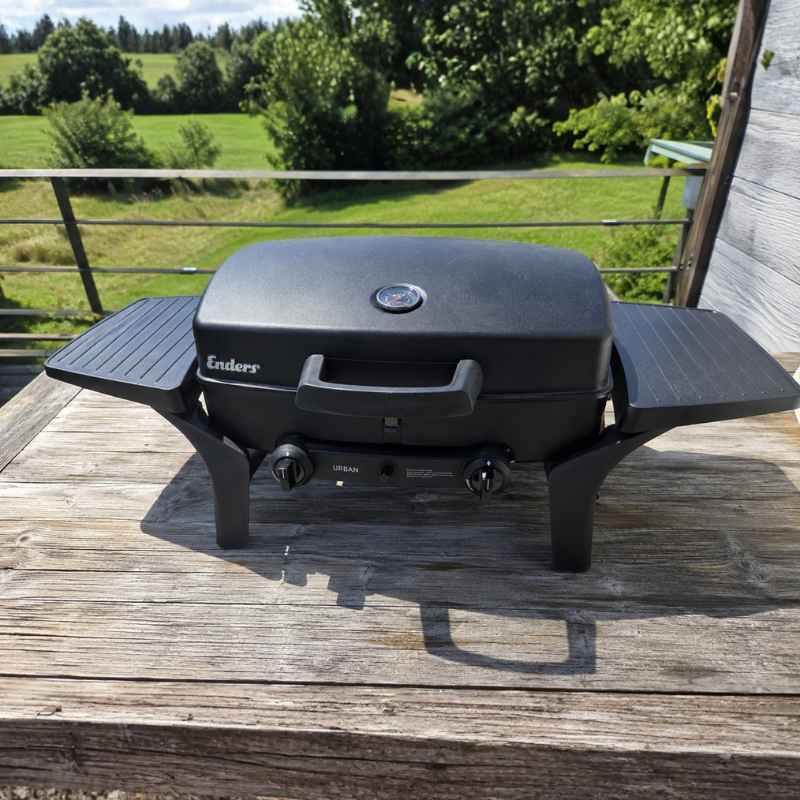 Schwarzer Enders Campinggrill auf Holztisch im Garten für Campingurlaub mit Van oder Wohnmobil