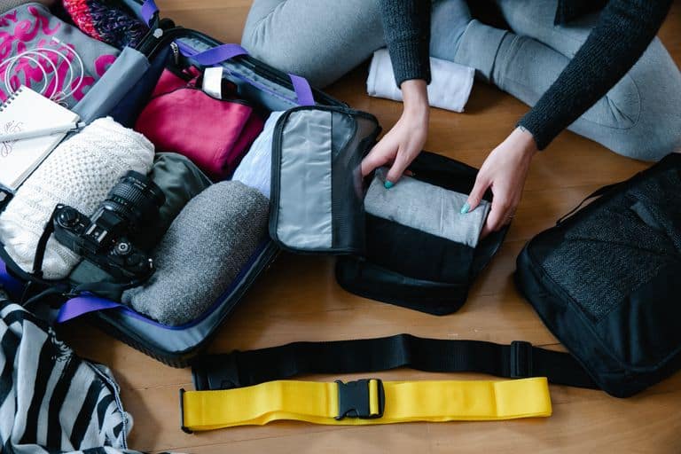 Koffer richtig packen: 10 einfache Tipps für mehr Platz im Gepäck a woman arranging clothes and accessories into a suitcase preparing for travel. 9185880 Du willst deinen Koffer richtig packen und Platz sparen? 🎒 Hier findest du 10 einfache Tipps für mehr Ordnung im Reisegepäck. Jetzt entspannt reisen!