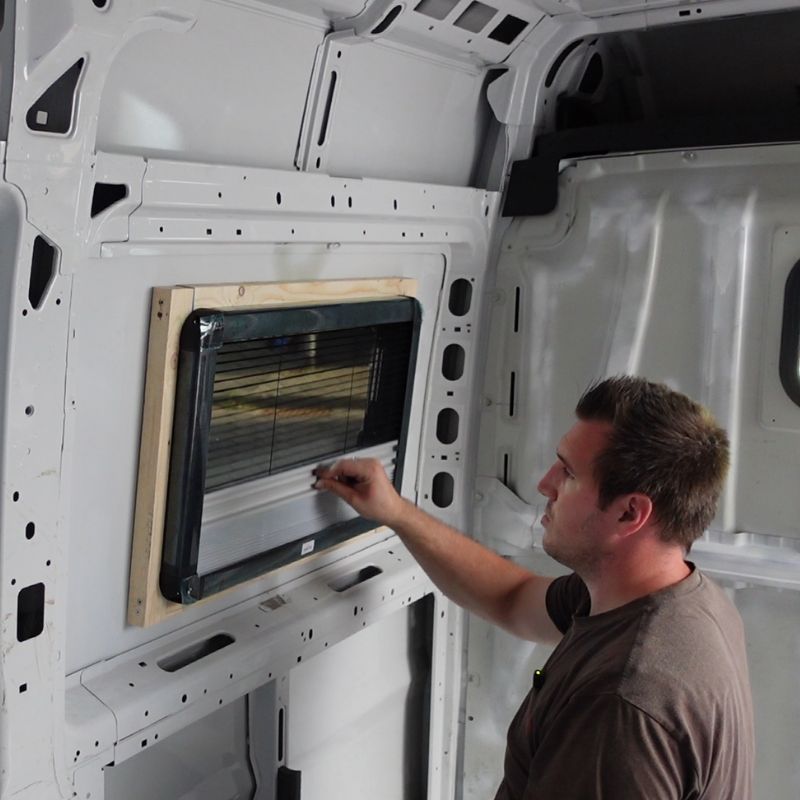 Mann installiert Fenster im Camper.