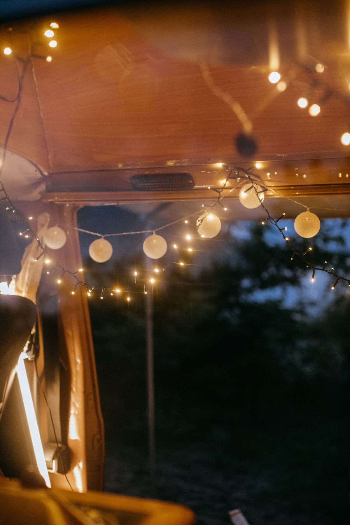 Camping-Ausrüstung: 50 geniale Dinge, die jeder Camper braucht a warmly lit camper van interior adorned with string lights creating a cozy ambiance. 8975476 scaled Camping Strom und Licht mit Powerbank und Campinglampe
