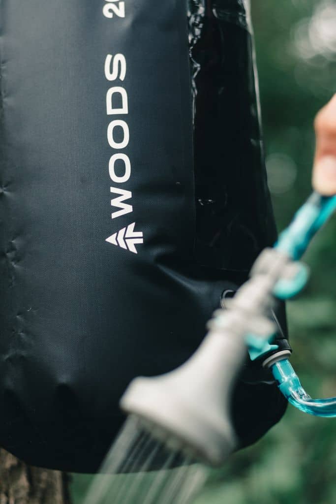 Camping-Ausrüstung: 50 geniale Dinge, die jeder Camper braucht detailed close up of a hand using a portable camping shower bag outdoors. 10772146 Wasserkanister und Hygiene Ausrüstung beim Camping
