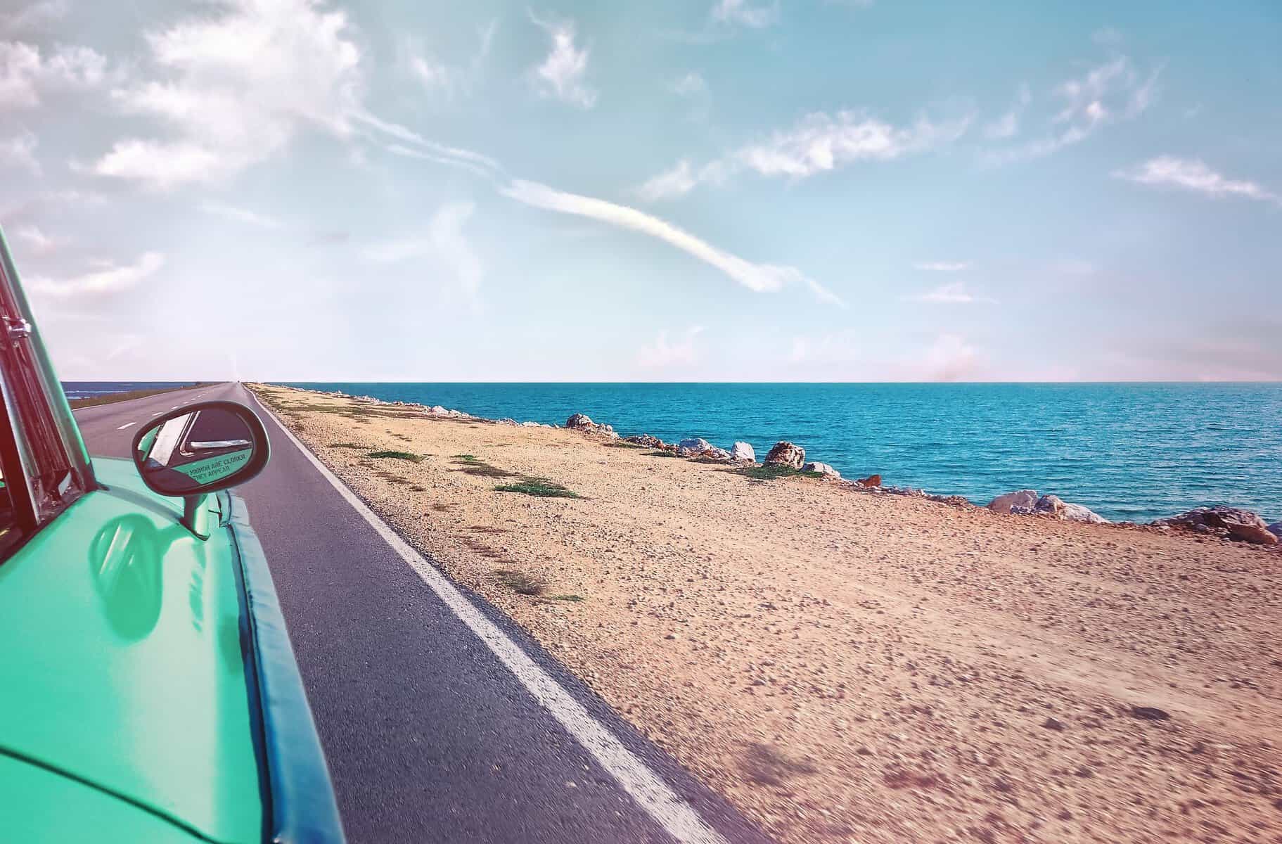 Mietwagen im Urlaub richtig buchen – Kosten, Versicherung & Ablauf a scenic road trip in a vintage car along a stunning seaside landscape under a clear blue sky. 1118448 scaled Mietwagen im Urlaub richtig buchen – Kosten, Versicherung & Ablauf