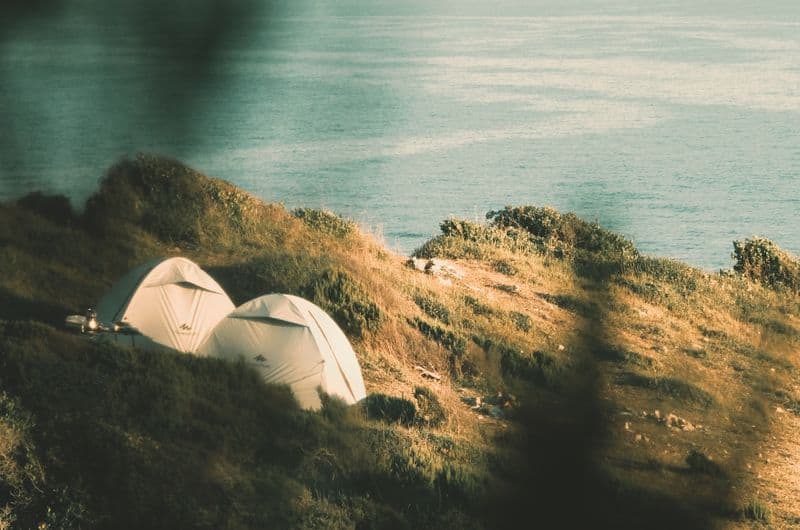 Camping-Ausrüstung: 50 geniale Dinge, die jeder Camper braucht tents on grassy cliff overlooking serene sea ideal for travel adventures. 14806017 Die schönsten Campingplätze in Italien 2026 – unsere persönlichen Erfahrungen