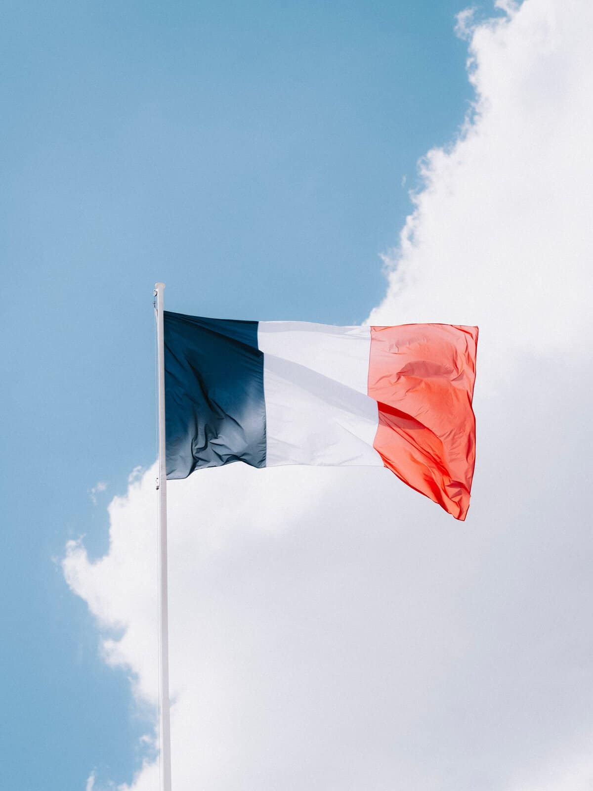 Beste Reisezeit für Frankreich: Wetter, Camping, Regionen & unsere Tipps the french flag waving in the wind set against a vibrant blue sky with clouds. 12467785 scaled Beste Reisezeit für Frankreich